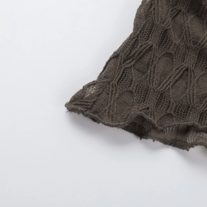 Detail of dark brown knit top with hollow lace pattern and scalloped wavy edges
