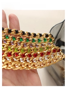 Detail of gold Cuban bracelets with multicolored square gemstones held in hand