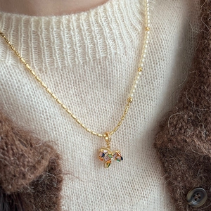 Gold-plated necklace with asymmetric pearl chain and colorful gemstone butterfly pendant