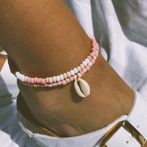 Detail of beaded anklet with pink and white beads and a natural shell pendant charm