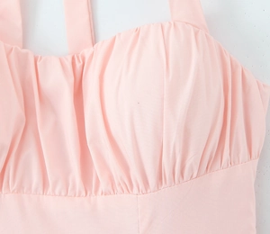 Detail of pink halter dress featuring pleated bust design and soft textured fabric
