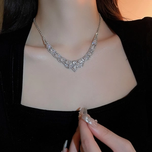 Gros plan du collier en V argenté avec cristaux étincelants porté par le mannequin
