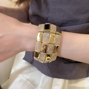 Detail of checkered acrylic and gold metal bangle with marble texture finish