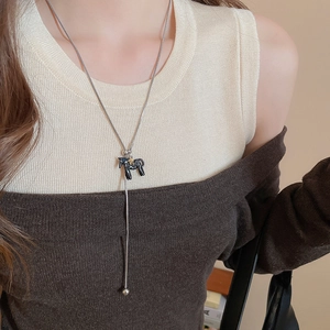 Close-up of long necklace with black horse pendant, gold star, and elegant tassel detail