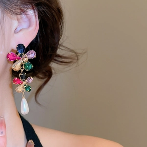 Close-up of gold-plated flower earrings with colorful crystals and teardrop pearls