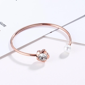 Detail view of rose gold flower bangle featuring a clear zircon and a white pearl accent