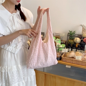 Detailed texture of pink gingham canvas tote bag in a lifestyle cafe setting
