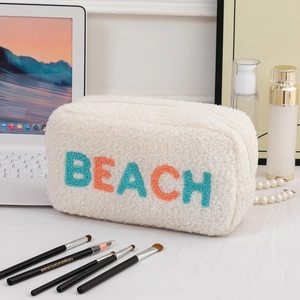Détail de la trousse de maquillage en laine d'agneau avec broderie BEACH et texture douce