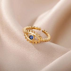 Detail of golden evil eye adjustable ring with blue stone on champagne silk