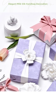 Close-up of elegant milk silk ribbon with white flowers and pink bow for gift wrapping