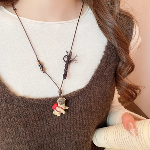 Detailed view of pug puppy pendant with red backpack and brown woven cord necklace