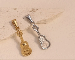 Detailed back view of ukulele pendants in gold and silver finish on stone texture