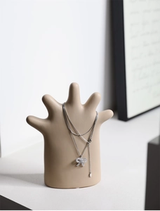Silver bow pendant necklace with zircons displayed on a ceramic hand jewelry stand