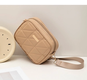 Detail of beige quilted crossbody bag with golden metal decor and fabric strap