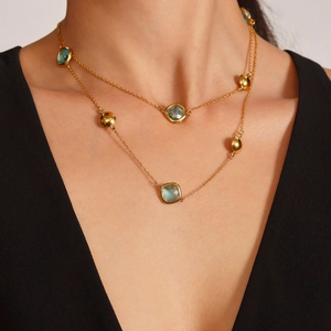 Elegante goudkleurige dubbellaagse ketting met lichtblauw glassteen en vierkante hanger