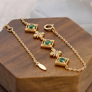 Makroaufnahme eines Vintage-Silberarmbands mit grünen Steinen auf einem Holzsockel
