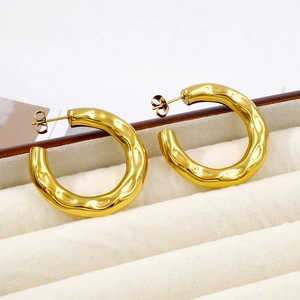 Detailed macro view of gold-plated hollow hoop earrings with hammered metal texture