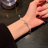 Detalle de pulsera de perlas con colgante de lazo dorado y pedrería brillante