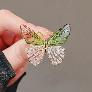 Golden butterfly brooch with translucent green wings and sparkling zircon crystals