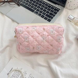 Close-up of pink quilted cosmetic bag with cute rabbit pattern in a workspace setting
