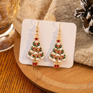 Detail of Christmas tree earrings with colorful enamel on a natural wooden display
