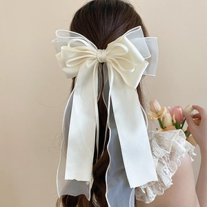 Back view of a large cream white ribbon bow hair clip with layered lace on a low ponytail