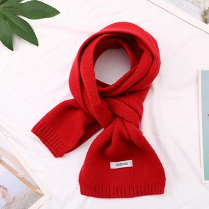 Detail of red knit scarf with ribbed texture and woven label on a lifestyle background