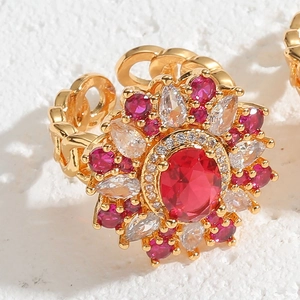 Detail of flower shaped gold ring with red oval gemstone and pave zircon cluster
