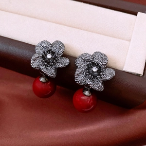 Macro shot of vintage flower earrings with dark silver base and red pearl drop detail