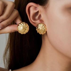 Detailed view of gold stainless steel stud earrings with spiral texture on model