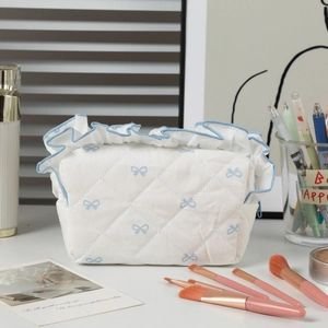 Detail of blue ruffled edge and bow pattern on quilted white makeup bag