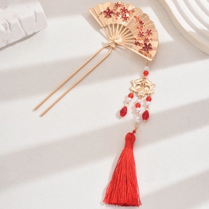 Close-up of golden Chinese hair pin with red floral pattern and beaded tassels