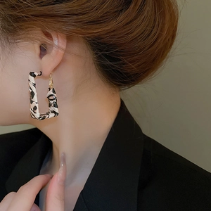 Close-up of geometric leopard print earrings on model with golden hooks and rectangular shape