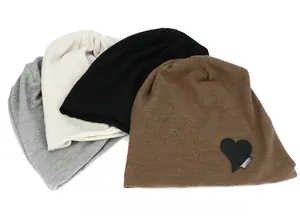 Detail showing knit texture and heart patch embroidery on four colorful beanies