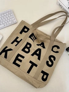 Khaki canvas tote bag with letter print shown in a minimalist aesthetic flat lay setup