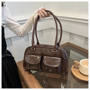 Detail of a dark brown glossy shoulder bag featuring retro double front flap pockets