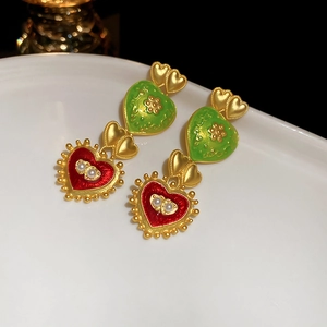 Detail of vintage heart earrings with green and red enamel and small pearl accents