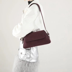 Detail of dark burgundy faux suede shoulder bag with magnetic flap and metal hardware