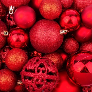 Close-up of red Christmas ball ornaments with matte, glitter, and hollow textures