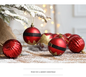 Gros plan de boules de Noël rouges avec motif ceinture de Père Noël sur sapin enneigé