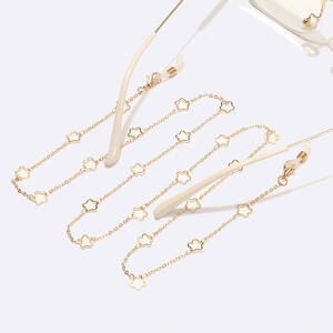 Detailed shot of golden eyewear chain featuring white floral motifs and non-slip rubber loops