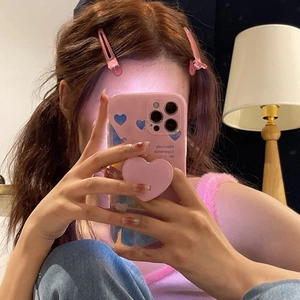 Mirror selfie showing a pink heart pattern phone case with a matching hair clip and grip