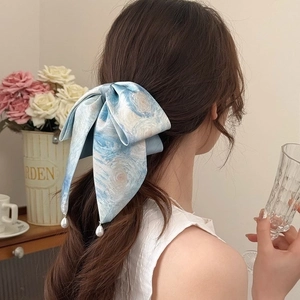 Starry night print satin bow hair tie with pearl pendants worn by a woman
