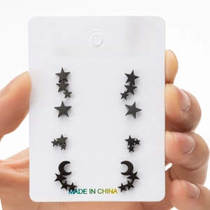 Close-up of black stainless steel star and moon stud earrings set on a display card