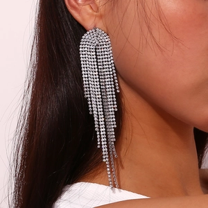 Macro detail of long silver zircon tassel earrings worn by a model for evening wear
