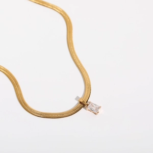 Detailed macro view of 18K gold plated snake chain with rectangular zircon pendant