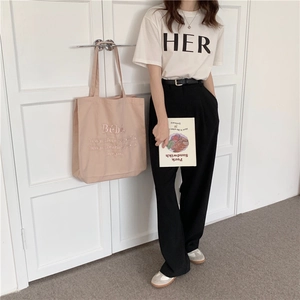 Detail der rosa Leinentasche mit Bebe-Stickerei und stilvollem weißem T-Shirt-Look