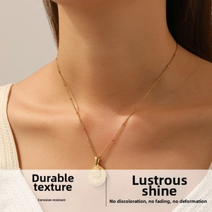 Detail of vintage gold-plated coin necklace featuring portrait relief and beaded chain