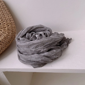 Close-up of pleated grey silk scarf with a retro crinkled texture on woven background