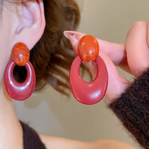 Detail showing vintage acrylic oval hollow earrings in amber and dark red tones